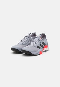 Gray athletic shoes with black accents, red details, textured mesh upper, and a cushioned sole. Lace-up closure and pull tab on the heel.