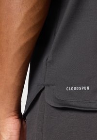 Mørkegrått stoff med en glatt tekstur, med en sidet slit og "CLOUDSPUN"-logoen i hvitt nær bunnkanten.