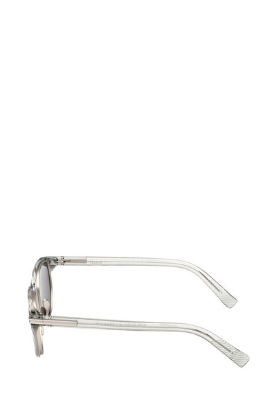 Przezroczyste okulary przeciwsłoneczne z oprawkami z octanu z okrągłymi soczewkami, wyposażone w cienkie metalowe zauszniki z teksturowanymi detalami. Subtelne gradientowe przyciemnienie na soczewkach.