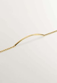 Pulsera en tono dorado con un diseño de barra curvada y un eslabón de cadena. Textura suave con un acabado brillante, destacando la estética minimalista.