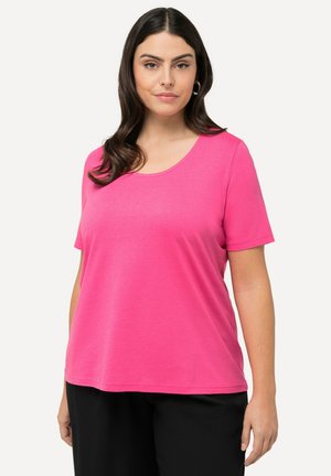 T-shirt rose à manches courtes avec un col rond, fabriqué en tissu doux, présentant une coupe décontractée et une texture lisse, associé à un pantalon noir.