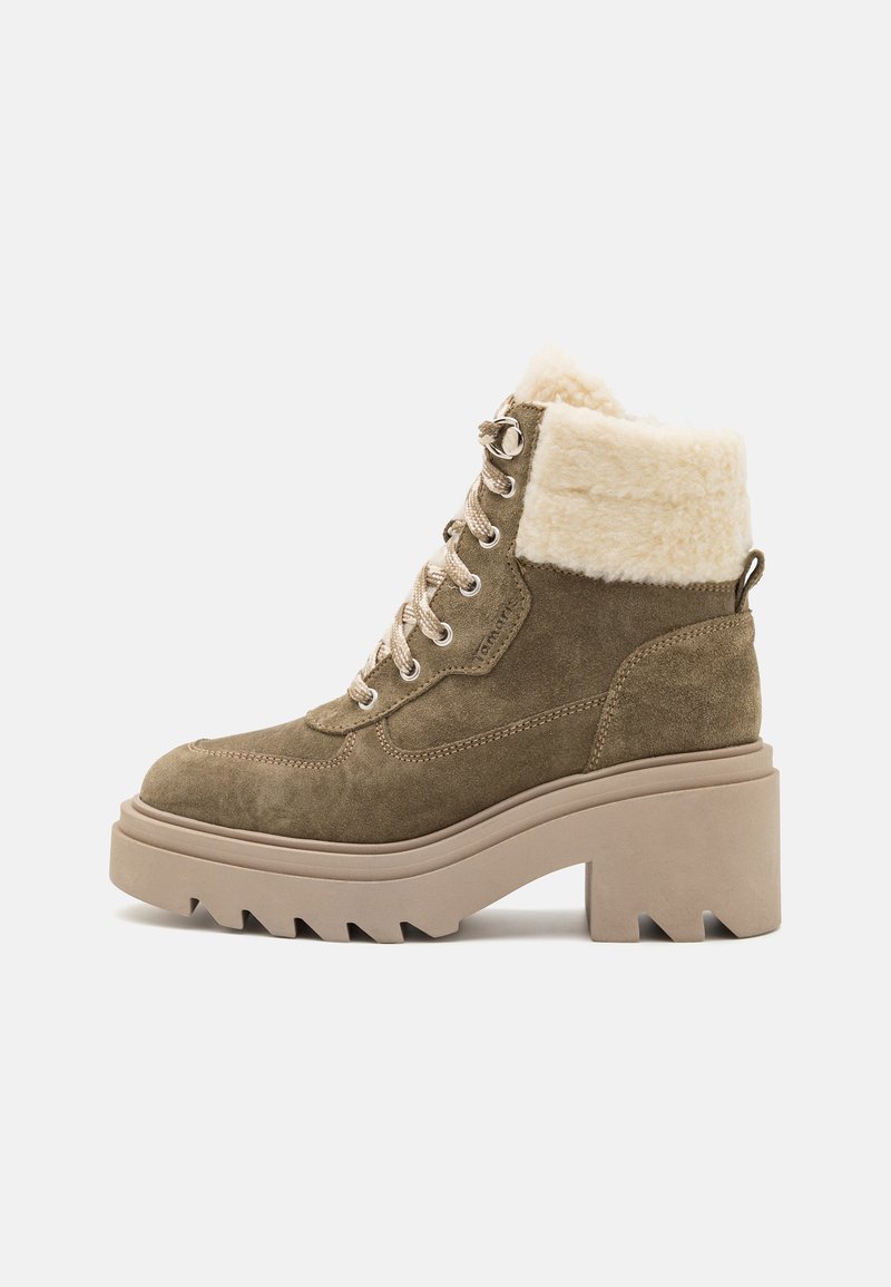 Bottes cheville vert khaki avec un revers en fausse fourrure, en daim texturé, et une semelle plateforme épaisse avec des rainures prononcées. Œillets en métal pour les lacets.
