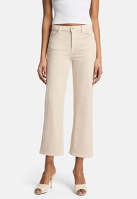 Jean beige à jambes larges avec une taille haute, présentant des poches avant et des ourlets droits. Fabriqué dans un tissu lisse et léger.