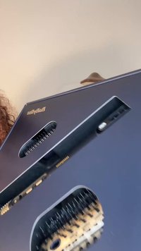 Svart hårrettende børste med et stilrent design, som har en keramisk overflate, jevnt fordelte børstehår og en kontrollpanel.