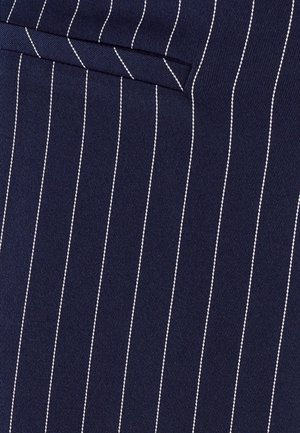Tessuto blu navy con righe verticali bianche; presenta una tasca singola nella parte superiore. Il materiale appare testurizzato e intrecciato.