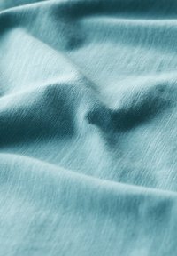 Light blue, textured fabric with soft, slightly wrinkled surface. The material appears smooth and lightweight with a subtle sheen.