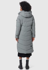 Longue doudoune grise avec un design en chevrons, capuche et poches latérales. Caractérisée par une texture lisse et un logo noir en accent au bas.