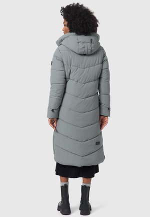 Lång grå pufferjacka med en chevrondesign, huva och sidofickor. Har en mjuk textur och en svart accentlogotyp vid fållen.