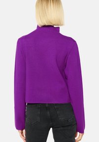 Suéter morado corto con mangas largas y cuello alto. Fabricado con un tejido suave, presenta un diseño simple sin patrones ni herrajes visibles.
