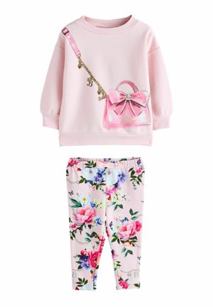Peuterkleding met lichtroze trui met een opdruk van een roze handtas met strik, gecombineerd met roze legging met bloemenpatroon.