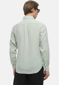 Camicia a maniche lunghe verde chiaro con colletto a bottoni, morbida al tatto e con orlo arrotondato, dotata di polsini con bottoni e vestibilità rilassata.