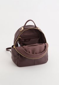 Kožený batoh v tmavé burgundské barvě. Hladký povrch, kovové prvky v zlatém tónu, horní držadlo a zipová vnitřní kapsa s měkkým podšívkou.