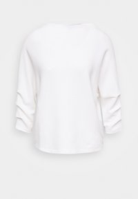 Vit ribbade topp med trekvartslånga ärmar, båthalsringning och en avslappnad passform. Texturerad tyg med subtila vertikala ränder.