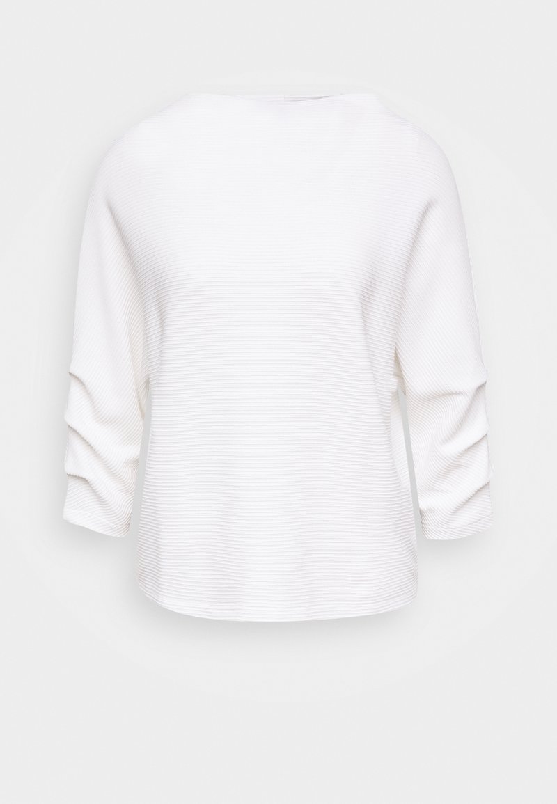 Vit ribbade topp med trekvartslånga ärmar, båthalsringning och en avslappnad passform. Texturerad tyg med subtila vertikala ränder.