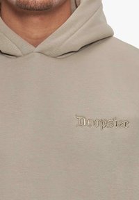 Beige hoodie lavet af blødt stof med hætte og fremtrædende broderet tekst "Dropsize" i lyse tråde på brystet.