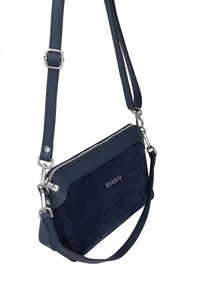 Granatowa torba z teksturowanej skórzanej powierzchni i zamszowym przodem. Posiada zamek błyskawiczny, regulowany pasek oraz metalowe akcenty.