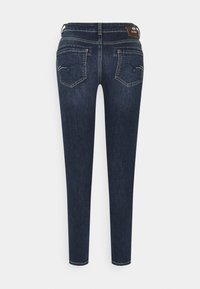 Jeans skinny azul oscuro con una textura suave, que presentan dos bolsillos traseros y detalles de costura sutiles. Diseño clásico de denim.