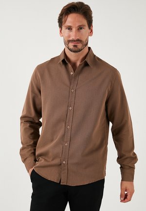 Camicia a maniche lunghe marrone con una texture sottile, chiusura a bottoni frontale e colletto classico. Presenta bottoni marroni e un orlo curvo.