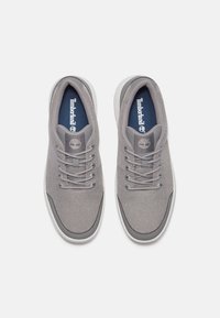 Zapatillas grises de material de malla con superficie texturizada, cordones redondos y una suela blanca en contraste. Logo de Timberland en la lengüeta.