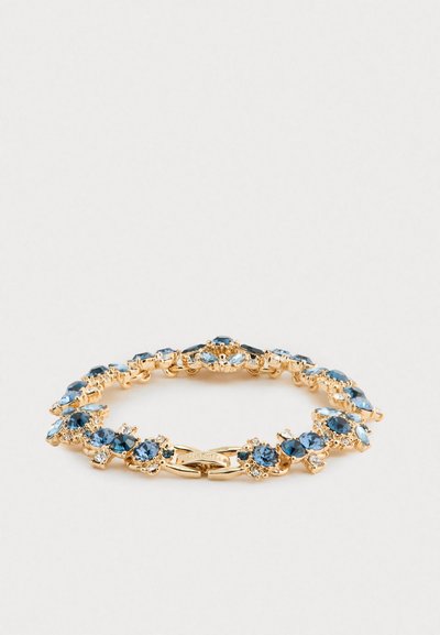 Gouden armband met blauwe en heldere edelstenen gerangschikt in bloemclusters op een witte achtergrond, sluiting zichtbaar met ingekrast merk.