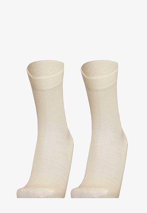 Knielange Socken aus einem weichen, gerippten Strickmaterial in einem hellbeigen Farbton. Sie haben ein schlichtes Design ohne Muster oder Akzente.