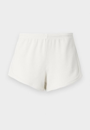 Pantaloni corti bianchi in tessuto a coste con vita elastica, caratterizzati da una vestibilità comoda e orlo curvo. Dettaglio della cucitura posteriore visibile.