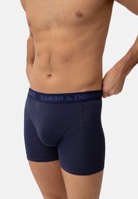 Boxers de color azul marino en tejido suave con una amplia cinturilla elástica que incluye texto. El diseño cuenta con un ajuste ceñido y un detalle de costura mínimo.