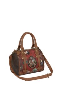 Sac à main rouge et marron avec une forme arrondie, en simili cuir, décoré de patchs sur le thème du voyage et avec des accents en or bien visibles.