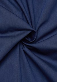 Marineblauwe stof met een gladde, licht gestructureerde oppervlakte, die een keperweefpatroon laat zien, gevouwen tot een spiraalvorm.