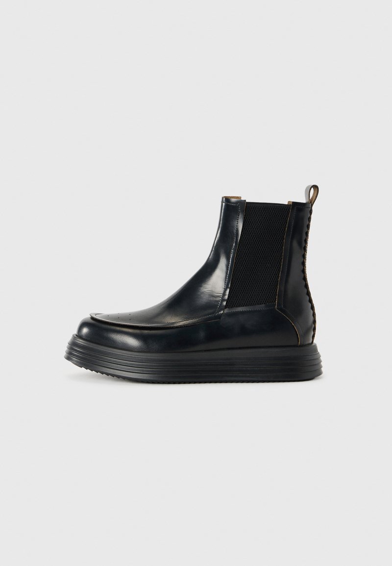 Mustad musta nahast ankle boot, millel on paks külgserva tallair, elastsed külgpaneelid, tõmbluku silmus ja dekoratiivne tagumine õmblus.