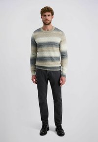 Gestrickter Pullover in Beige, Grau und blauen horizontalen Streifen; Rundhalsausschnitt, lange Ärmel; kombiniert mit dunklen Jeans und schwarzen Schuhen.