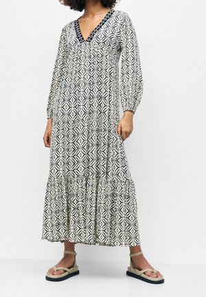 Maxi šaty ze vzorované látky, s hlubokým výstřihem do V, dlouhými nafouklými rukávy a vrstveným lemem. Barvy zahrnují krémovou, námořnickou modř a černou.