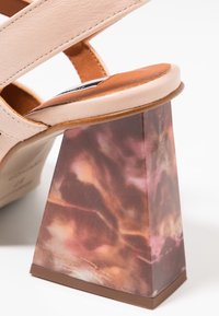 Béžové kožené sandály na vysokém podpatku se širokým páskem a robustním podpatkem, který má mramorový hnědý a růžový vzor.