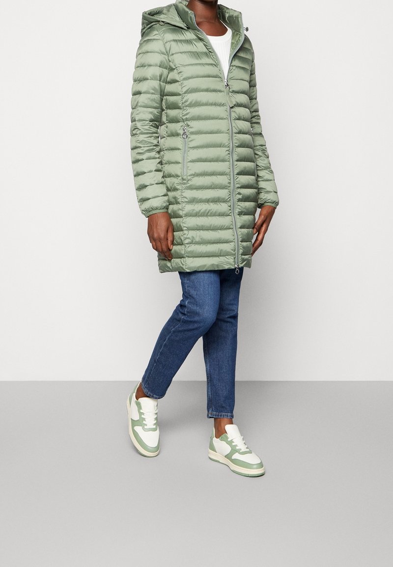 Lys grøn pufferjakke med hætte, som har lodrette syninger, lynlås foran og sidelommer. Sammen med blå jeans og sneakers med grønne accenter.