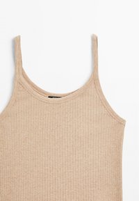 Top in maglia beige a coste con spalline sottili, realizzato in tessuto morbido, caratterizzato da un scollo a giro e un design aderente con una leggera elasticità.