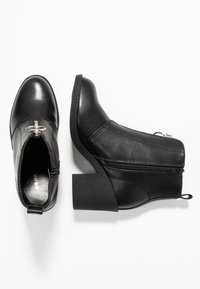 Bottes  à cheville en cuir noir avec un bout arrondi, une fermeture éclair latérale et un talon bloc. Dotées d'une texture lisse et d'une quincaillerie argentée décorative.