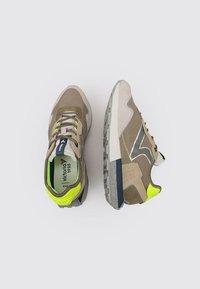 Baskets dans des tons beige et olive, avec un mélange de daim et de maille, des accents jaune fluo, des détails réfléchissants et une semelle en caoutchouc texturée.