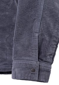 Szara rękawica z materiału sztruksowego z pionowymi żebrami i detalem guzika przy mankiecie. Miękka tekstura z czystym, zorganizowanym designem.