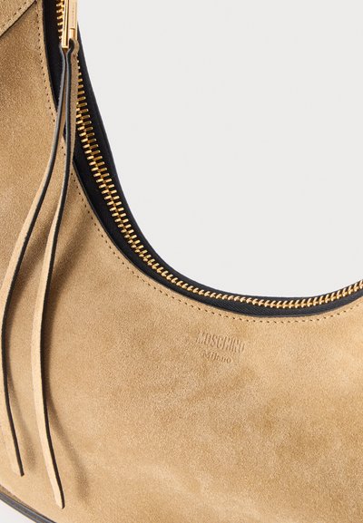 Sac à main en daim beige avec fermeture éclair dorée et doublure intérieure noire, avec un petit logo Moschino Milano embossé et des tirettes de fermeture éclair en daim.