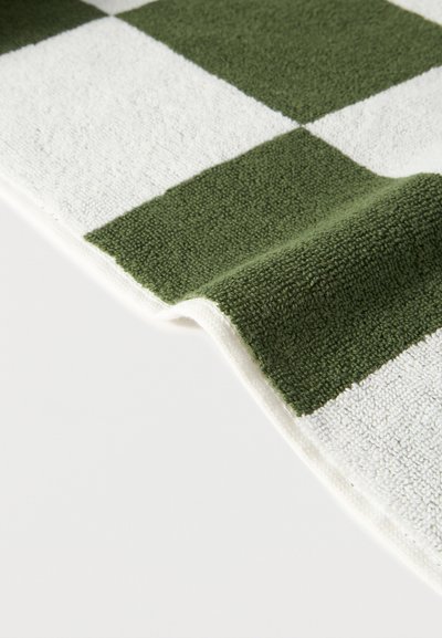 Κοντινό πλάνο υφάσματος με πράσινο και λευκό καρό, υφή με μαλακή, βρόχινη επιφάνεια, ελαφρώς ανυψωμένη σε μια άκρη, σε λευκό φόντο.