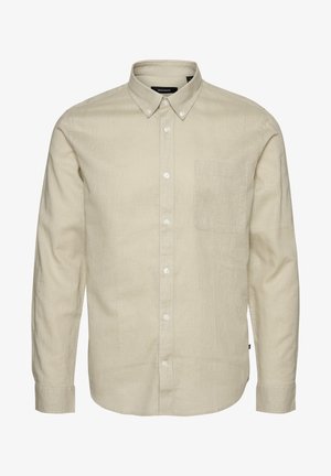 Camicia beige a maniche lunghe con bottoni, realizzata in un tessuto textured, con una tasca sul petto e orlo arrotondato. I bottoni sono bianchi e rotondi.