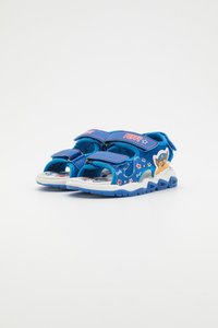 Sandales bleues pour enfants avec des sangles velcro, présentant un design de chien ludique, une tige texturée et une semelle en caoutchouc blanche avec des imprimés colorés.