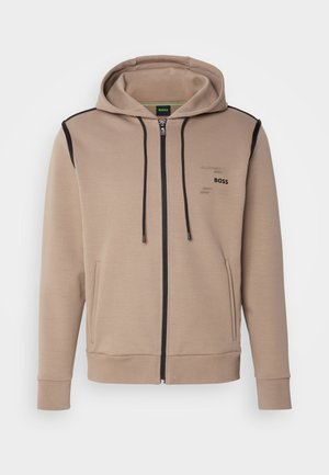 Hooded sweatshirt in beige cotton blend, featuring a black zipper, side pockets, and minimalistic logo detailing on the chest.