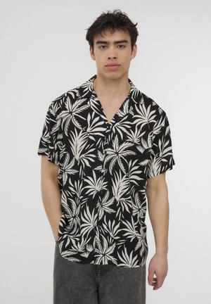 Camicetta nera a maniche corte con motivo di foglie tropicali bianche, tessuto leggero, colletto con scollatura a V e orlo dritto.