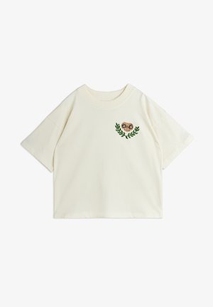 Kreemikat värvi lühikeste varrukatega T-särk ümmarguse kaelusega, millel on rinnal tikitud öökulli disain, mida ümbritsevad rohelised lehed.