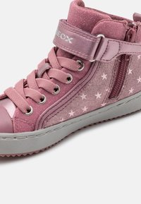 Różowe sneakersy za kostkę z wzorem gwiazdek, tekstylny cholewka, wiązanie na sznurówki i rzep, gumowa podeszwa oraz metaliczne akcenty. Zawierają zamek błyskawiczny z boku.