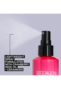 Redken lichte spray in een felroze fles met een zwarte nozzle, met tekst die cranberryzaadolie en ceramiden benadrukt.
