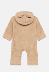 Beige teddy fleece baby jumpsuit med hette som har to små runde ører og lange ermer, vist flatt bakfra.