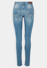 Tievie džinsi gaiši zilā džinsā ar izbalējušu apdari. Iekļauj aizmugurējās kabatas ar izliekto šuvju dizainu un ādas etiķeti uz jostasvietas.