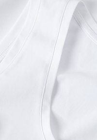 Gros plan sur un tissu blanc avec des coutures et des lignes de couture visibles, mettant en valeur la texture et la qualité du matériau du vêtement.